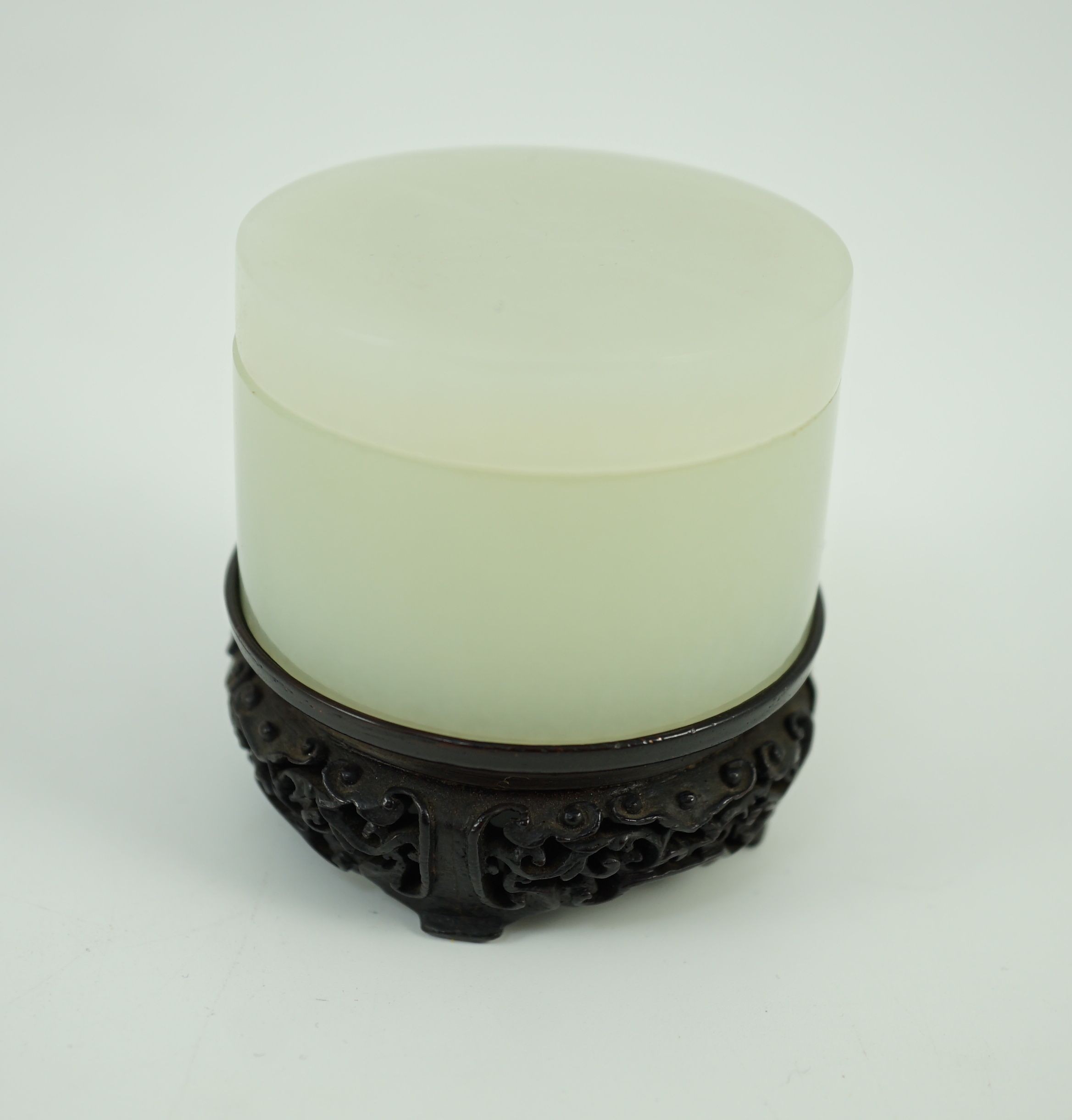 A Chinese pale celadon jade cylindrical box and cover, 18th/19th century, 5.3 cm diameter, zitan wood stand